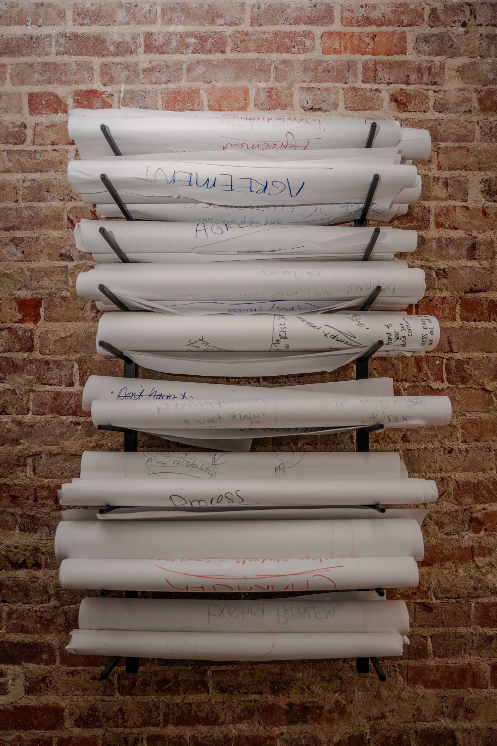 Rolled-up strategy sessions racked on the studio wall